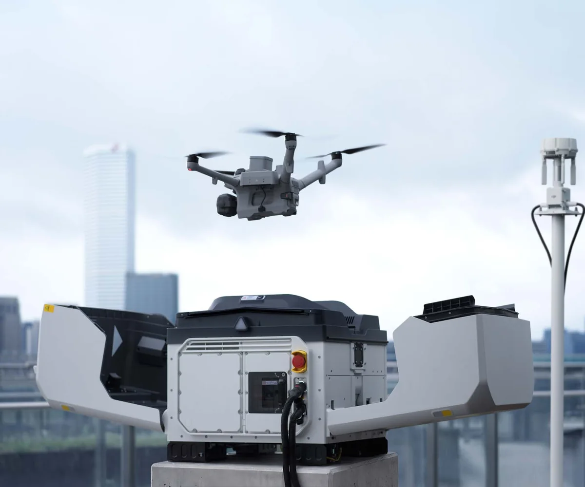 Illustration: DJI Dock 4 mit abhebender Drohne vor einer Stadtkulisse
